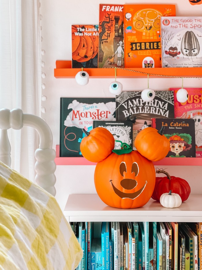 Mickey Mouse pumpkin in front of Halloween books and bookshelves next to bed