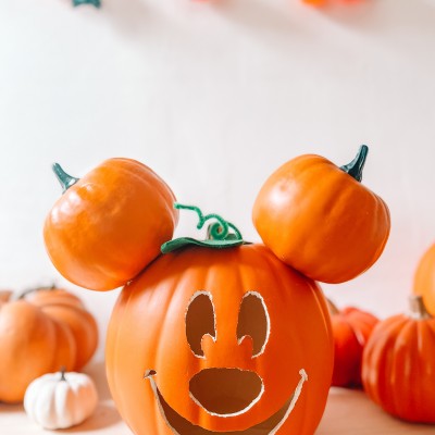 How To Make A Mickey Mouse Pumpkin Mickey Mouse pumpkin in front of pumpkins, white wall and pumpkin lights