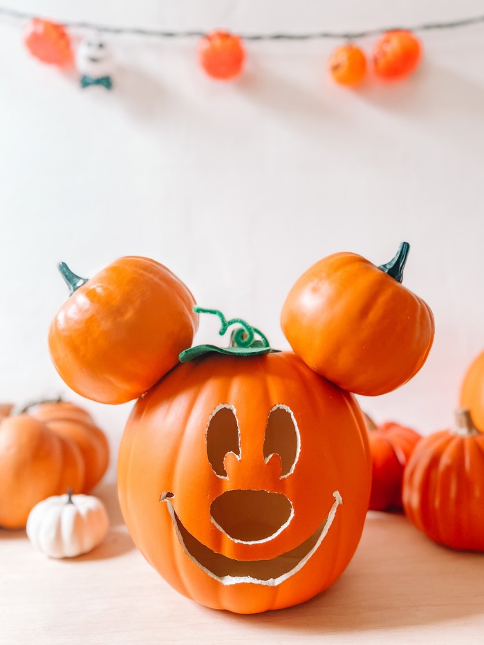 Mickey Mouse pumpkin in front of pumpkins, white wall and pumpkin lights
