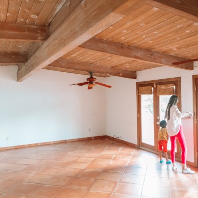 We Bought A House In... Palm Springs! Mom and child in empty house with terracotta floors and wood beamed ceilings