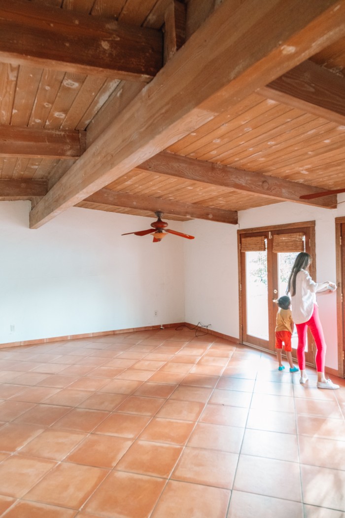 Mom and child in empty house with terracotta floors and wood beamed ceilings