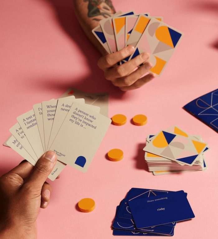 People playing "where should we begin game." Cards have prompts for players to answer.