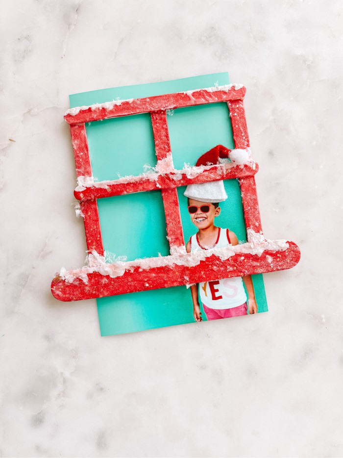 Popsicle stick window with fake snow and photo of child
