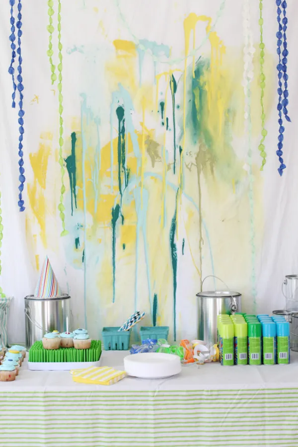 Paint splatter birthday party backdrop and dessert table.