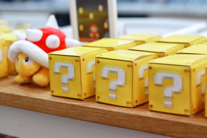 question mark box party favors stacked on a table with Spiney plush