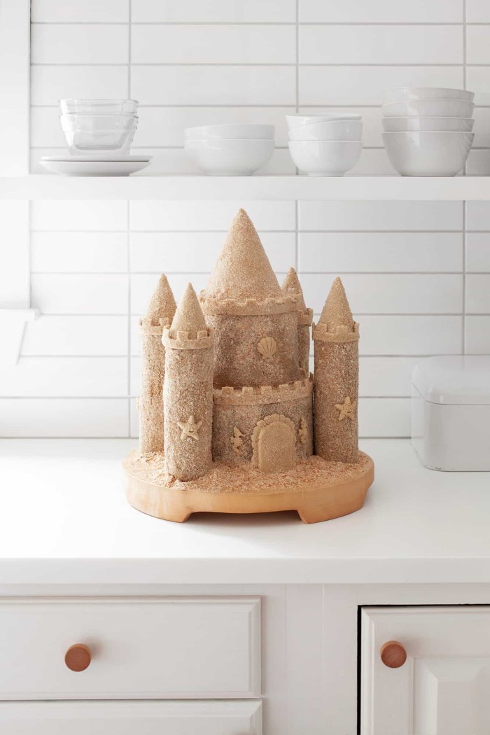 Sandcastle cake on a stand on the counter.