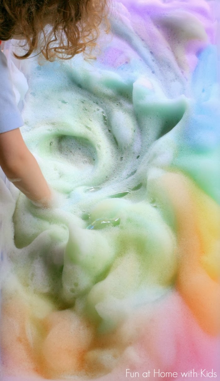 Rainbow foam bubbles swirled by a child.