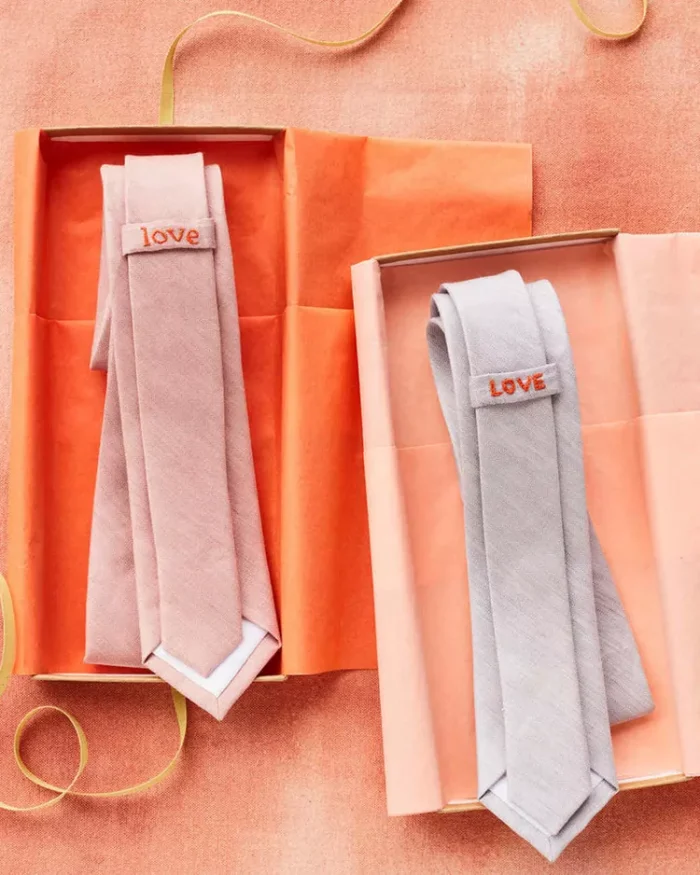 Two boxes with two ties in them that both say "love" on the back.