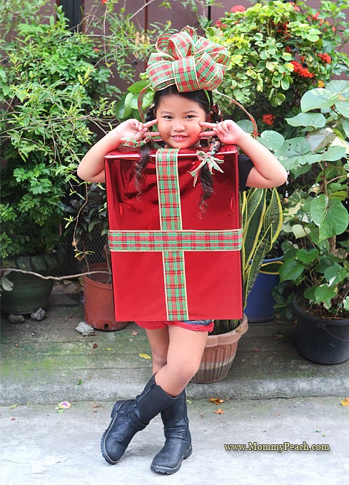 Christmas Present Costume Girl dressed as a Christmas present with a bow on her head.
