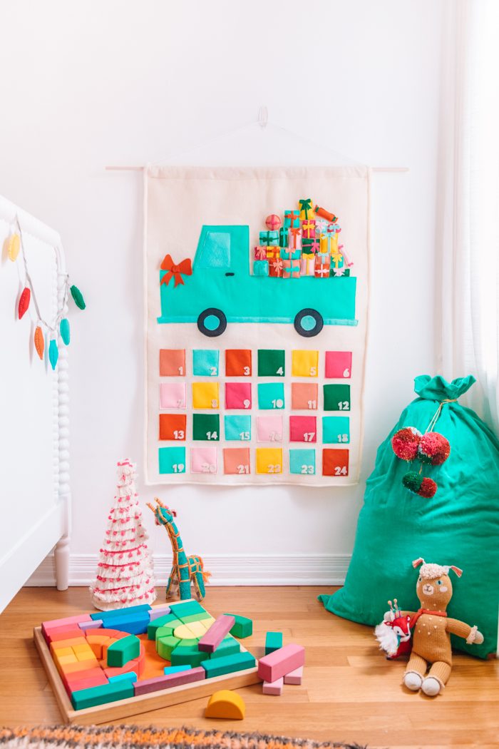 Christmas Bucket List Ideas Felt advent calendar with a truck design on it hanging on a wall.