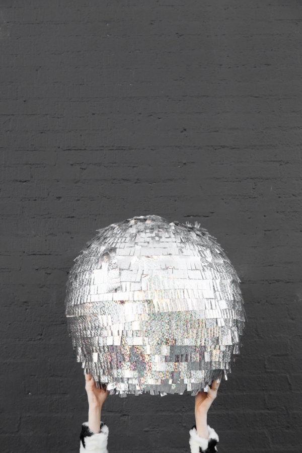 Disco Party Hands holding a disco ball pinata in the air.
