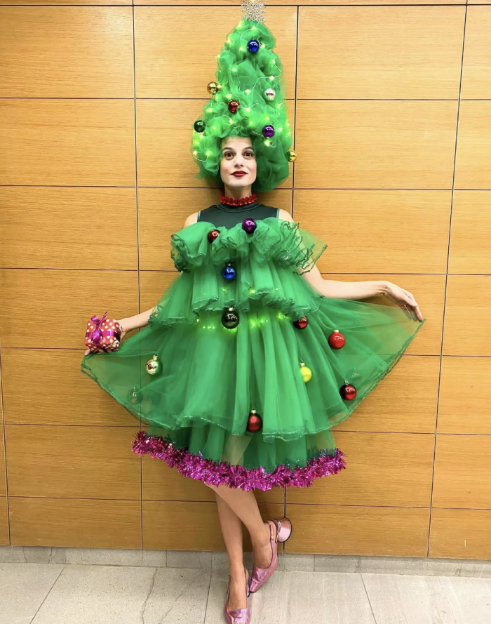 Christmas Tree Costume Woman standing in front of a wall wearing a Christmas tree costume made of tulle.