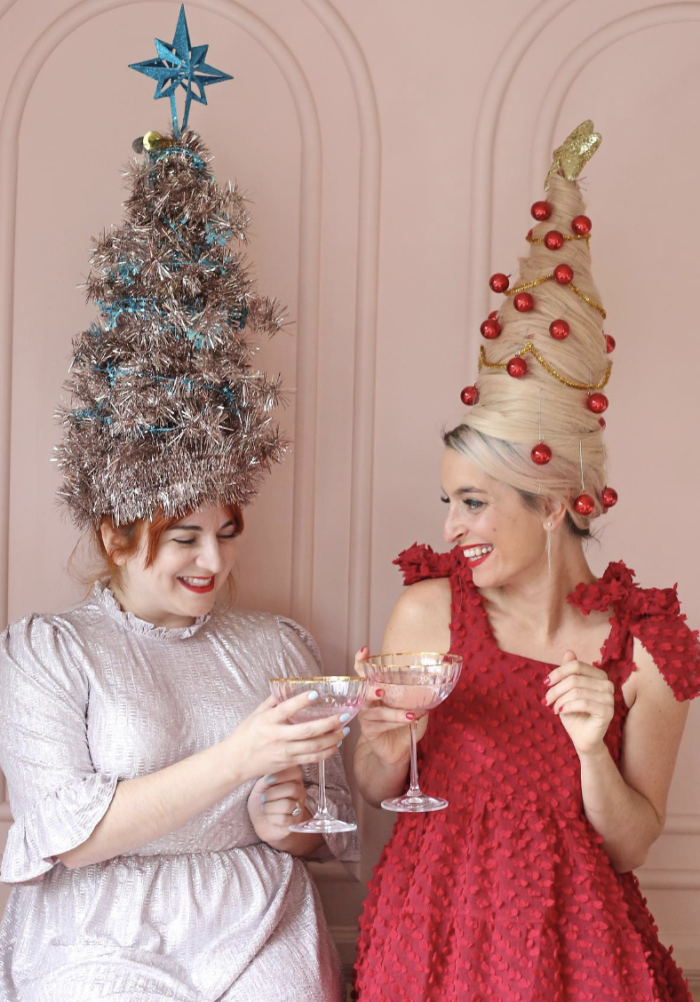Christmas Tree Wigs Costume Two woman holding drinks with large tree-shaped wigs on their heads.
