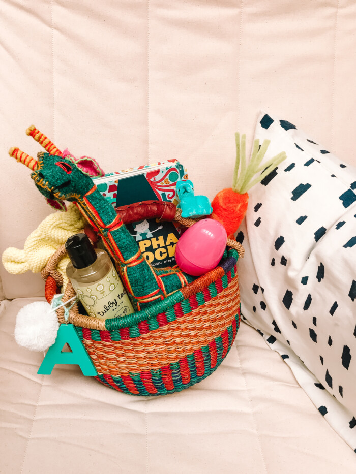 Best Easter Basket Woven basket with easter goodies in it next to a pillow.