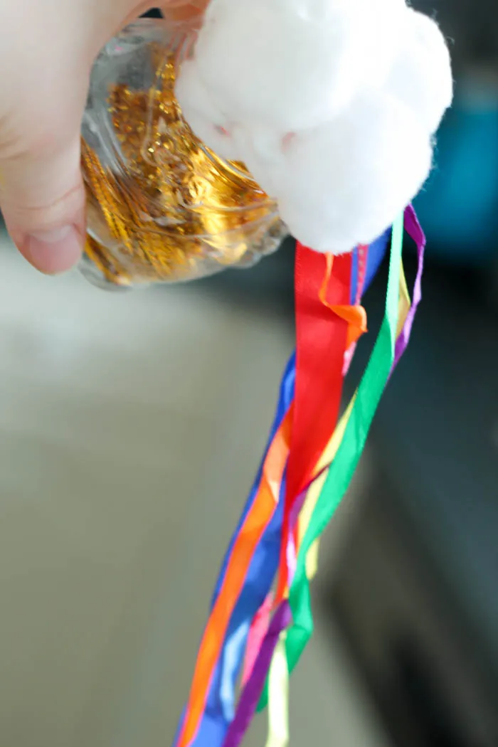 Hand holding a pot of gold rainbow shaker. 