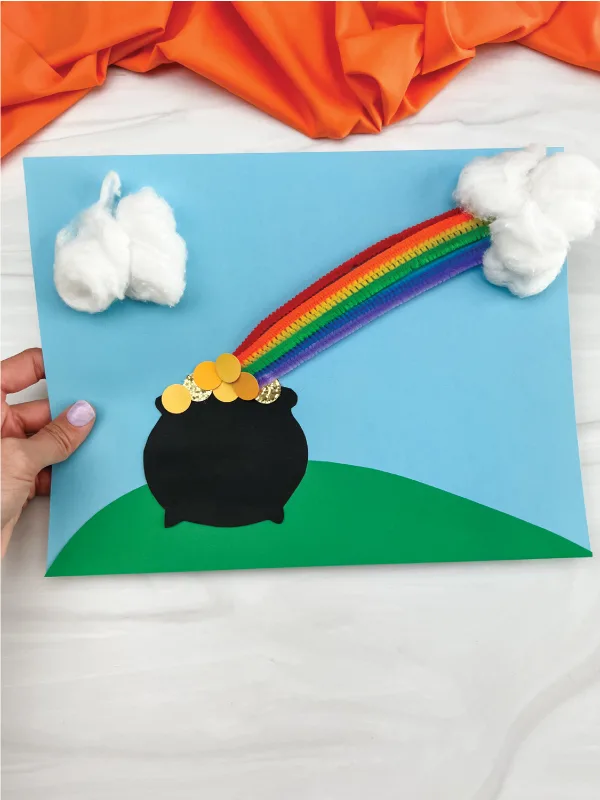 Pot of gold with rainbow coming out of it on a blue paper. 