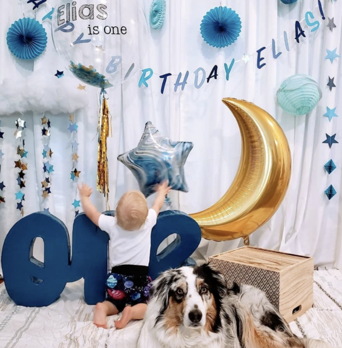First Trip Around the Sun Birthday Party Baby grabbing a star shaped balloon that is surrounded by moon and star decorations.