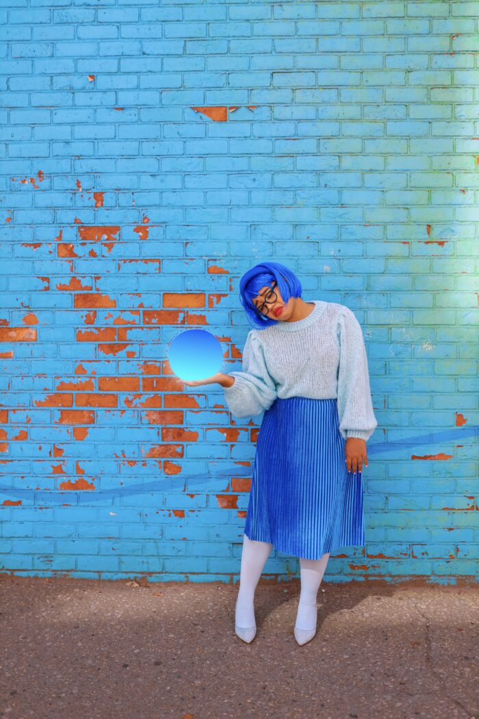 Inside Out Costumes Woman dressed as "sadness" from Inside Out in front of a blue wall.