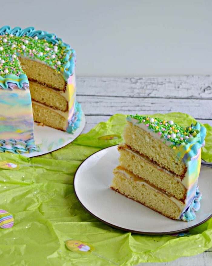 Watercolor Party Watercolor triple layer cake with a slice on a plate.