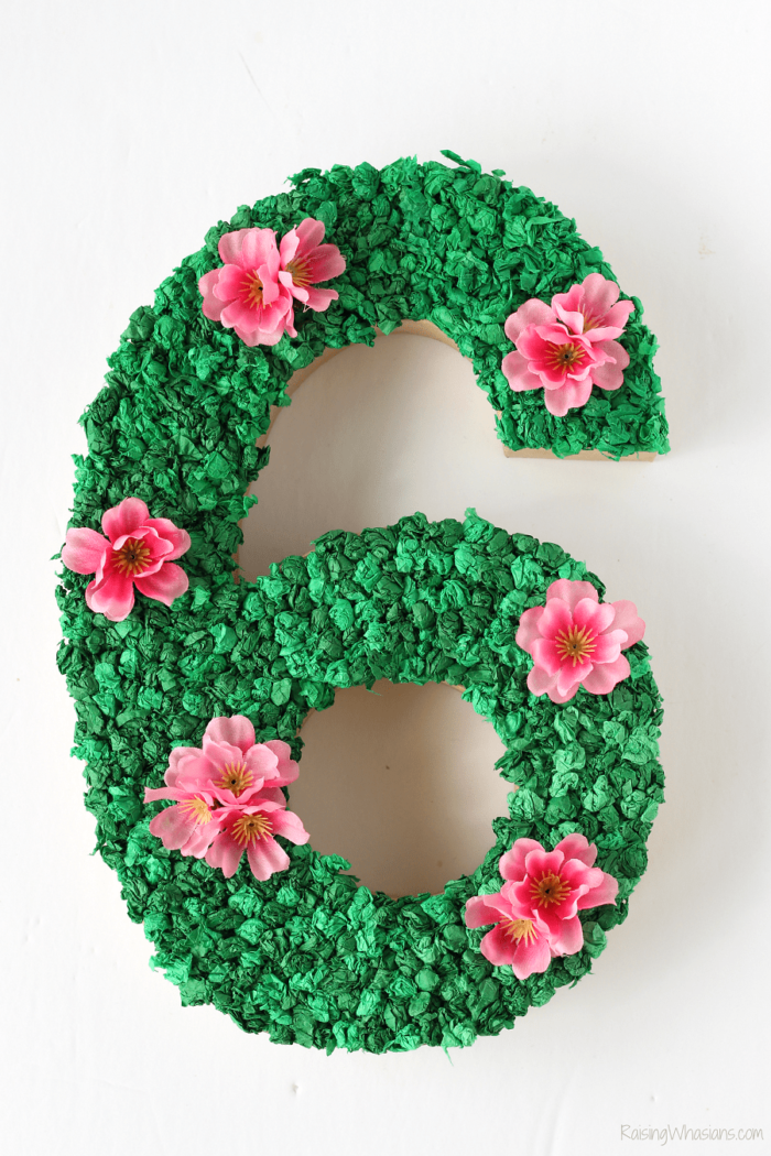 Moana Party Decoration Number 6 decorated with green tissue paper and pink flowers.