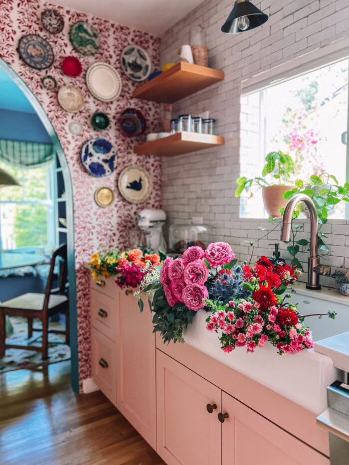 kitchen with flowers in sink and pink cabinets