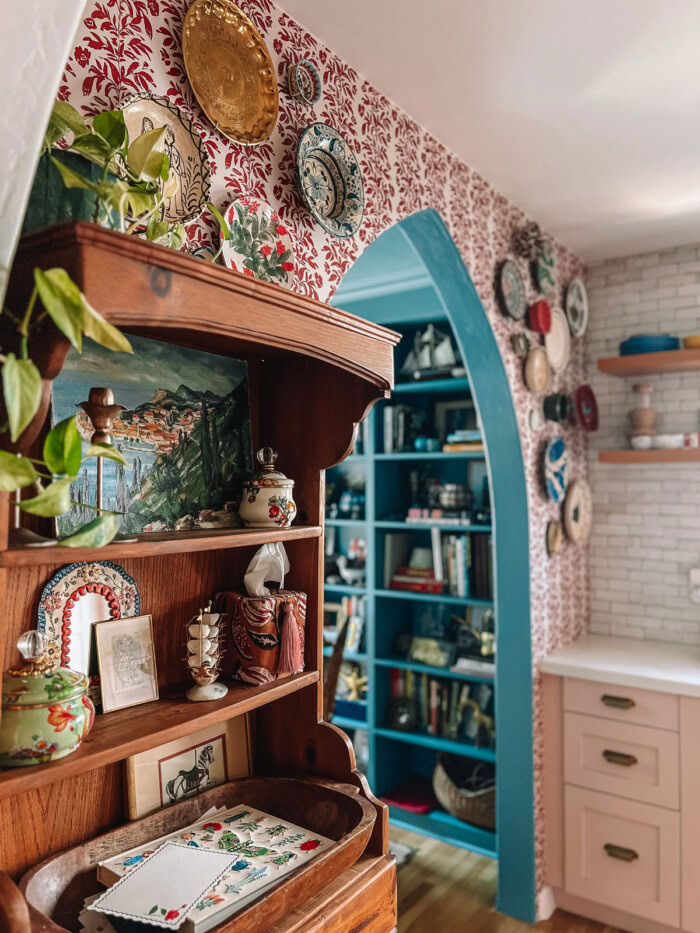archway and hutch with red stripe wallpaper behind it in kitchen