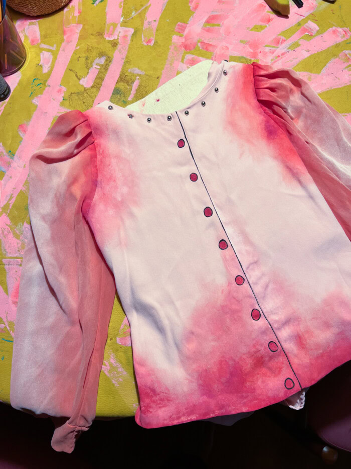 pink painted shirt laying on yellow table